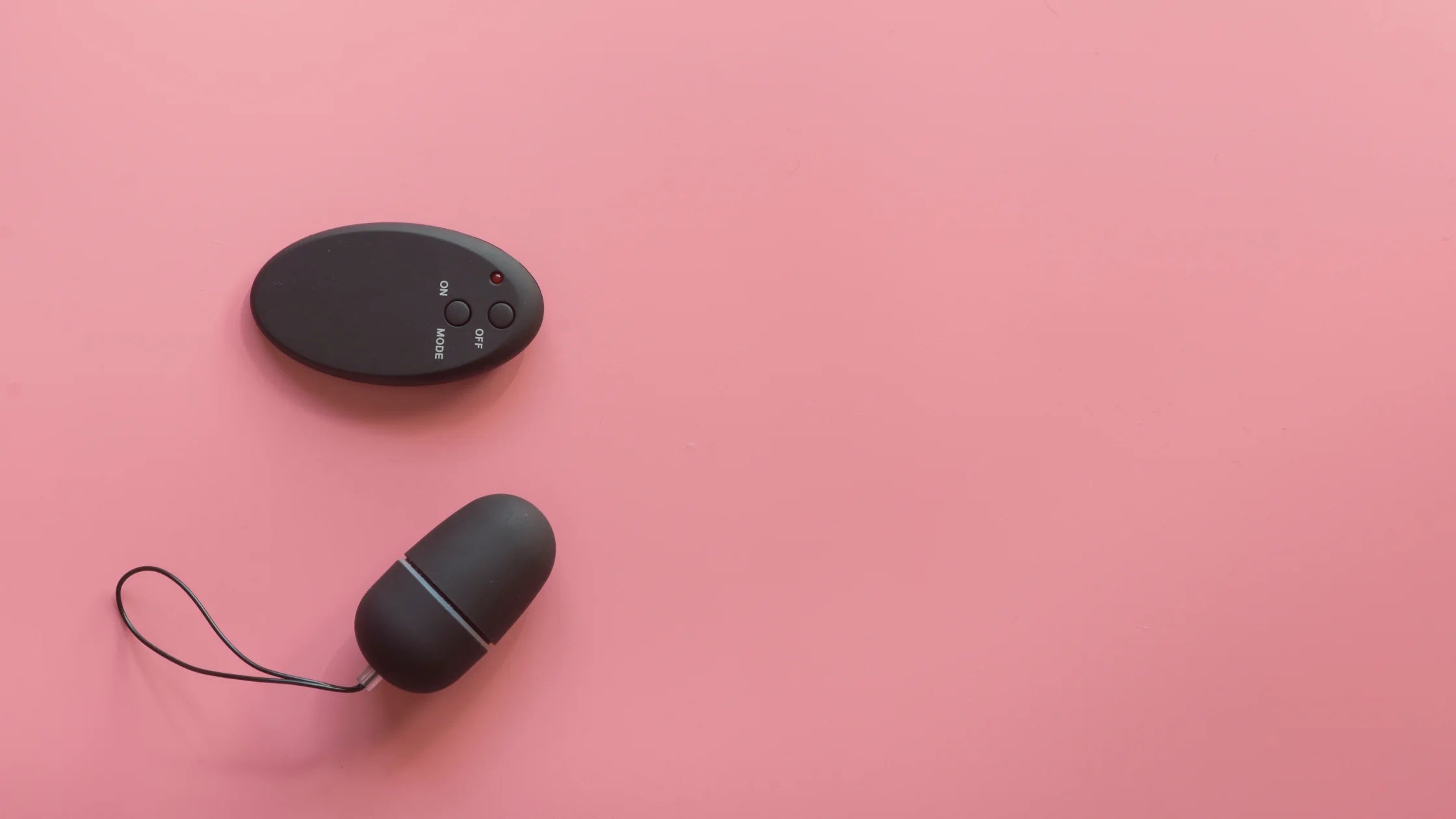 black egg vibrator with remote pink background sex toy numen wellness