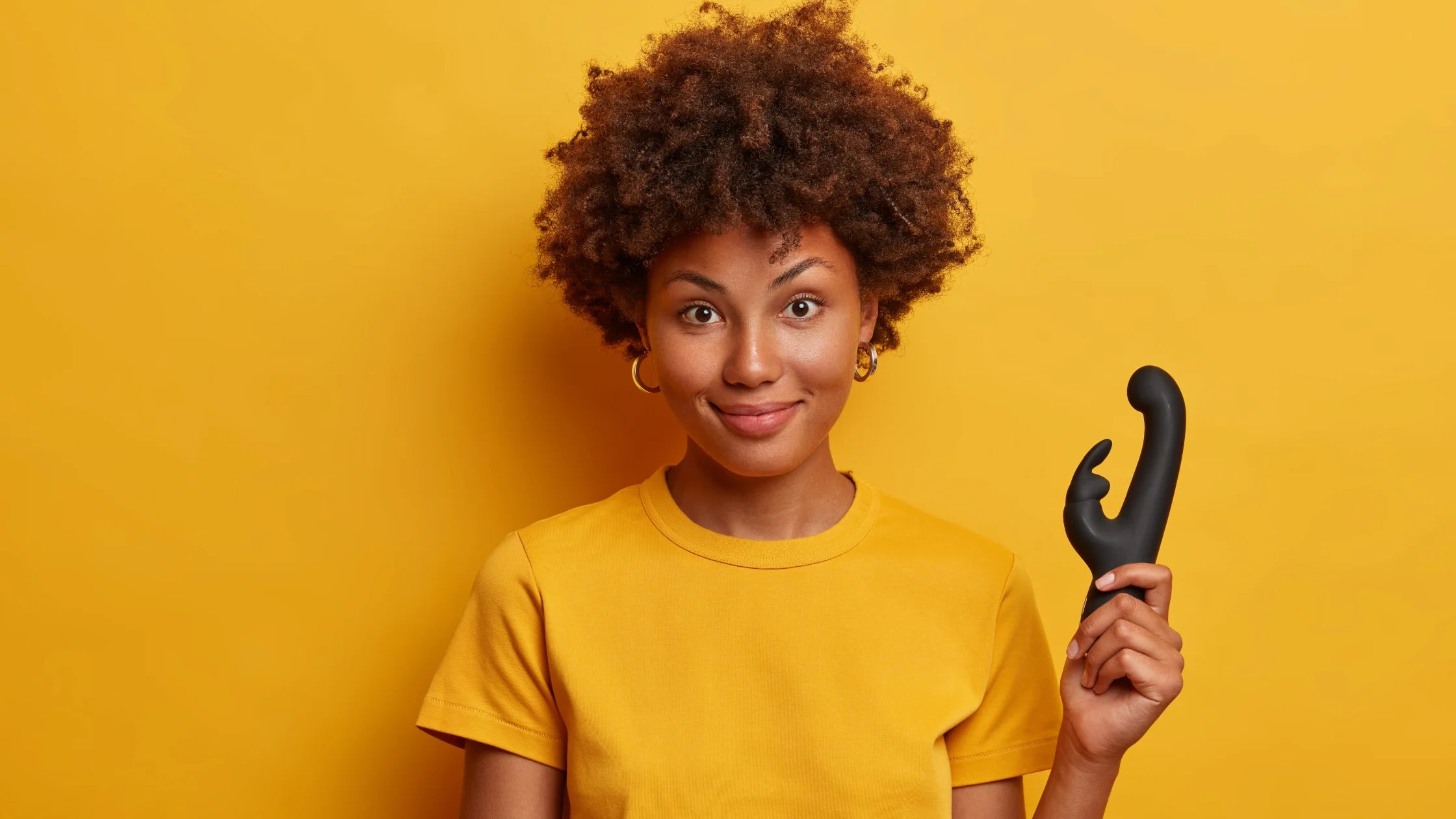black girl with curly hair holding black rabbit vibrator yellow background sex toy numen wellness
