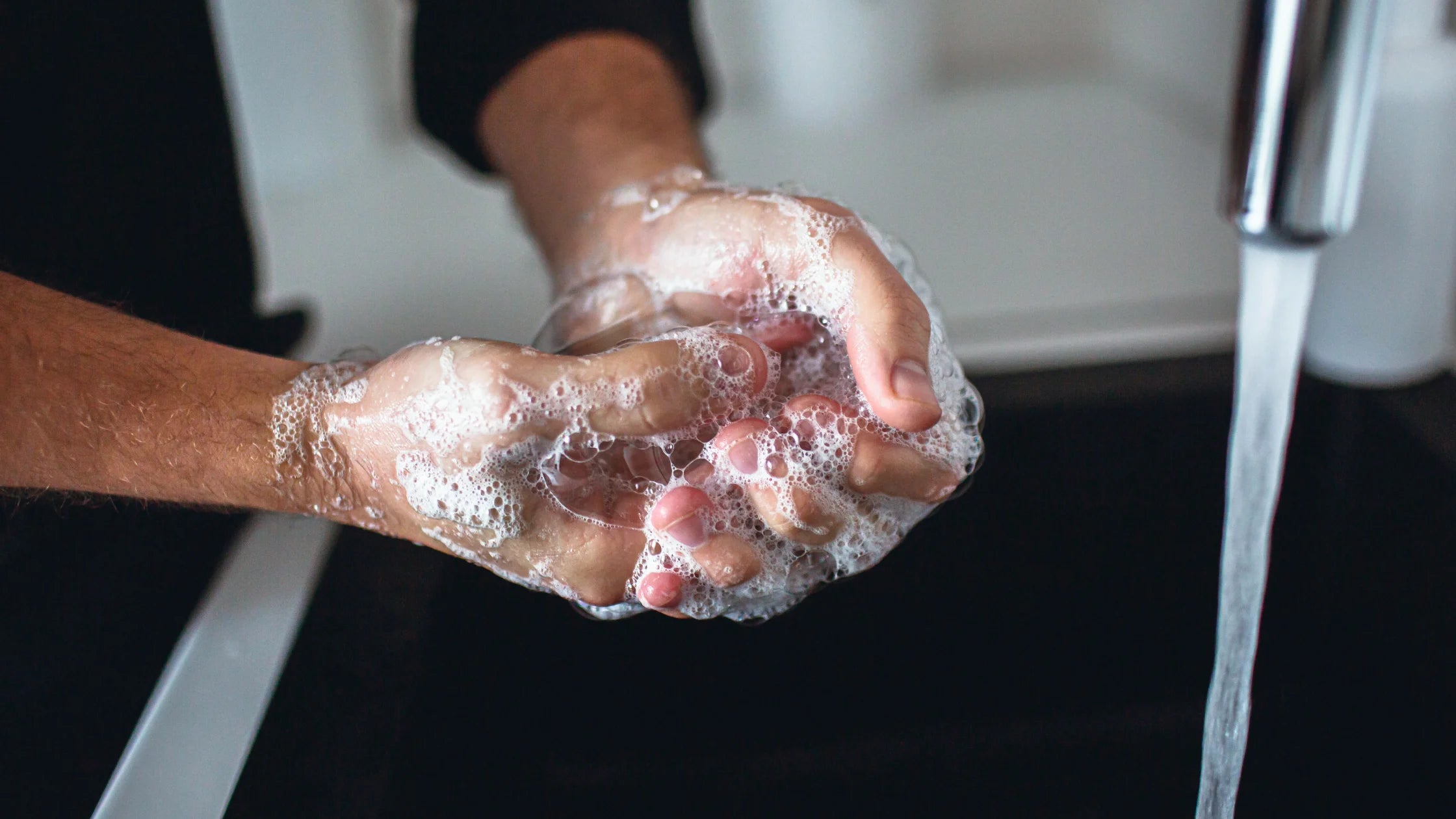 man hands being washed with soap and water numen wellness