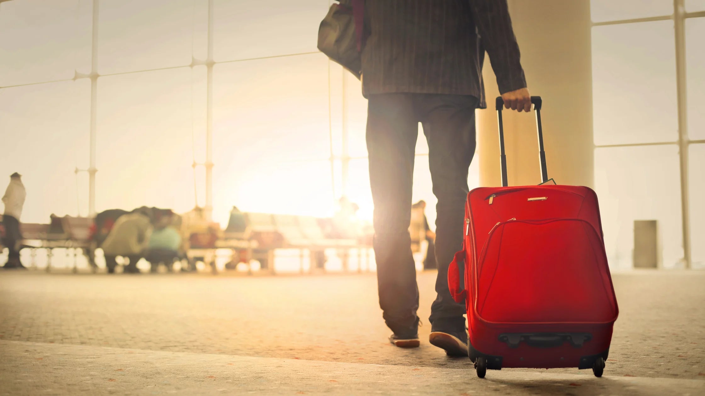 man standing with roller luggage at airport numen wellness