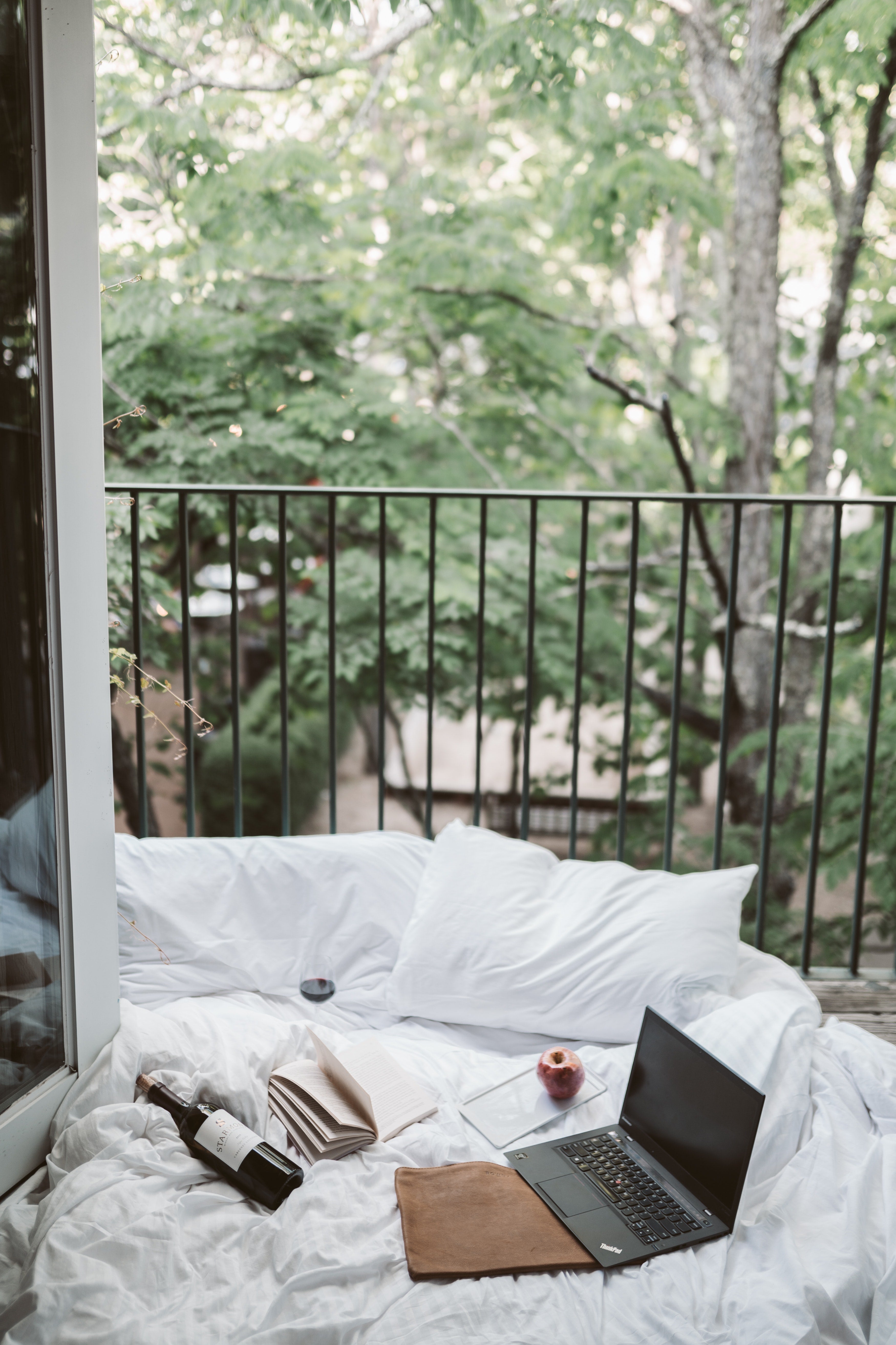 white-sheets-laptop-wine-book-apple-balcony-numen-wellness
