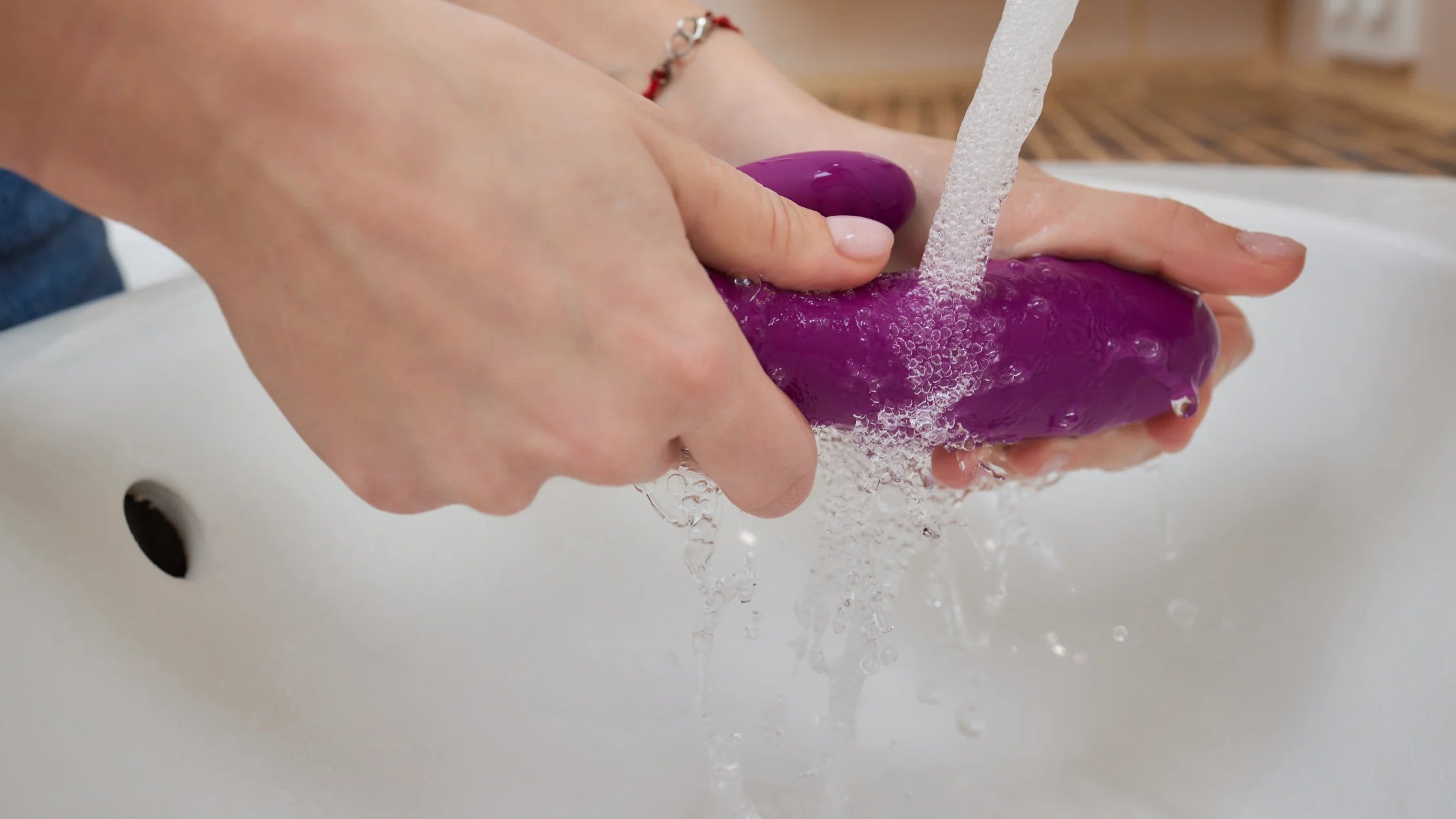 cleaing purple dildo in sink with water numen wellness