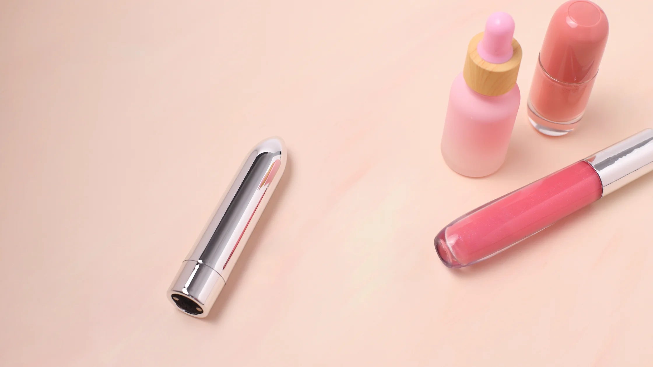 grey bullet vibrator next to makeup kit pink background sex toy numen wellness