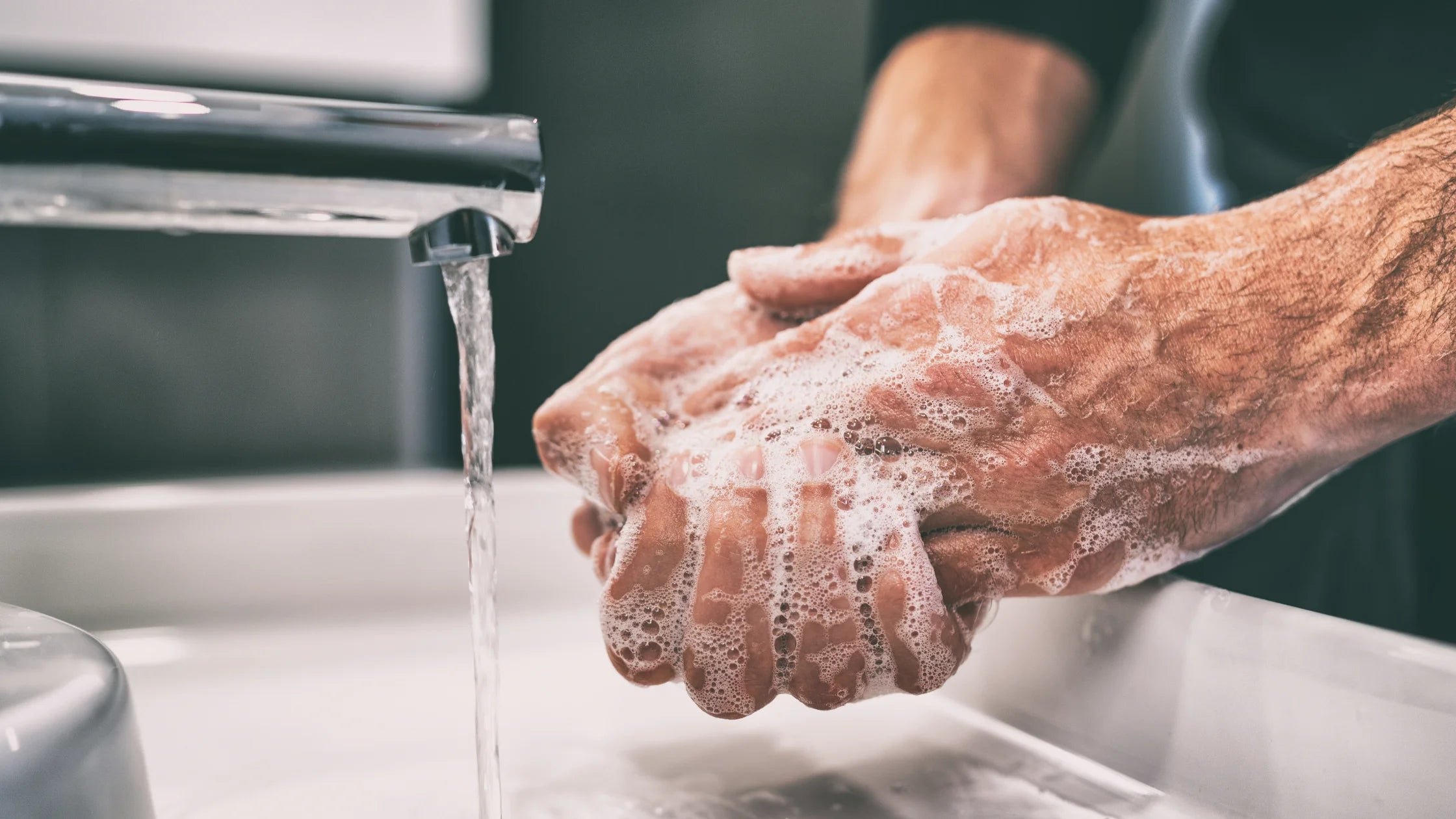 man washing hands in sync with water & soap numen wellness
