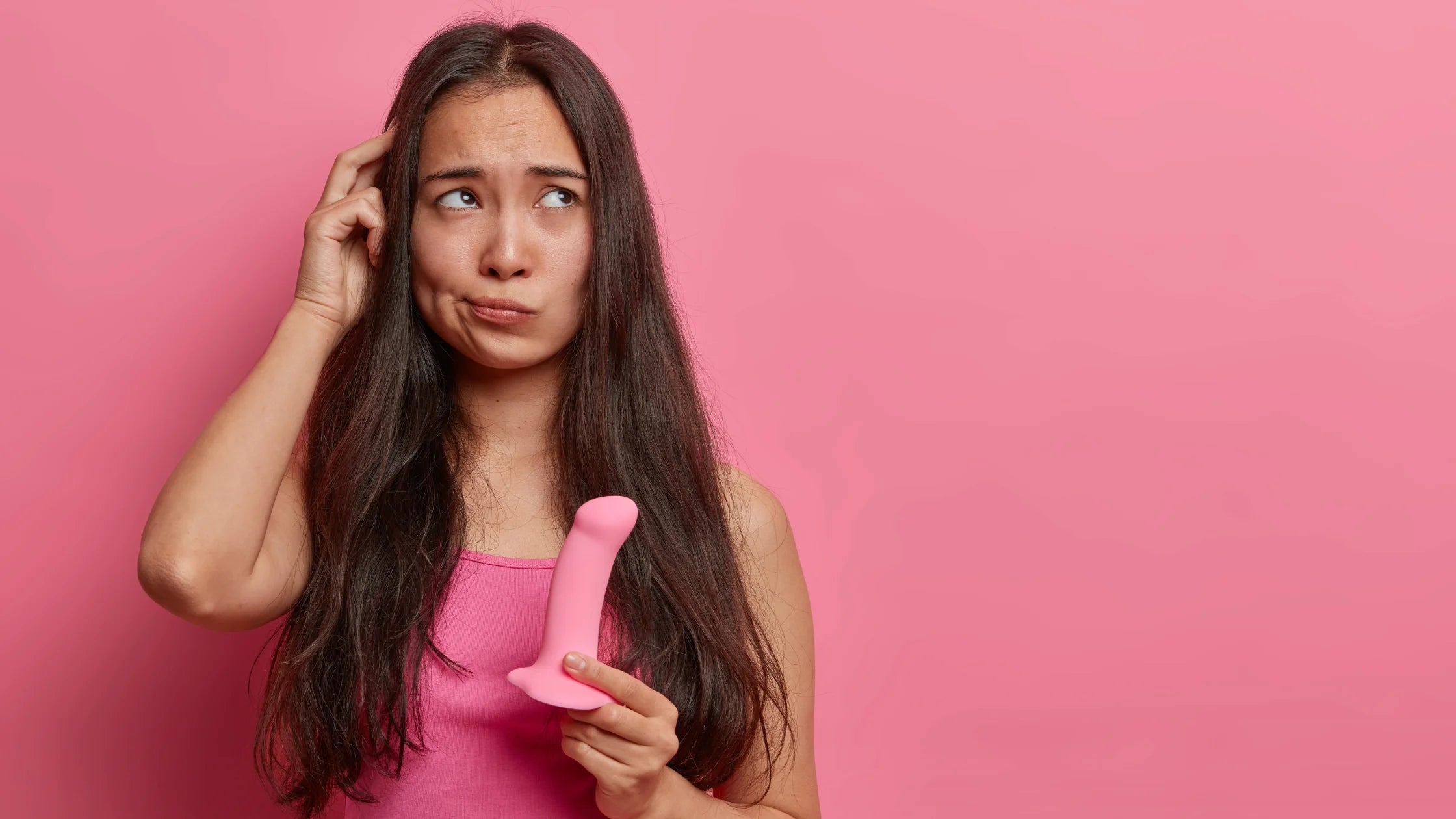suction cup dildo pink women holding thinking pink background sex toy numen wellness